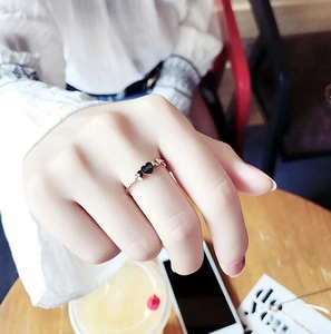Rose gold Love ring with black heart pendant worn on woman hand in a cozy lifestyle setting