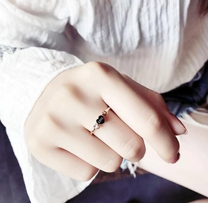 Detail of rose gold minimalist ring with black love heart and small white zircon inlay