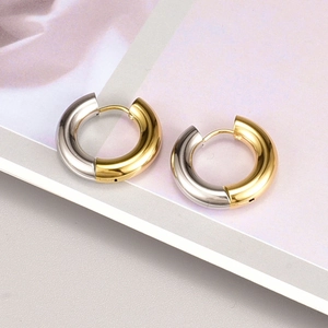 Detail van dikke tweekleurige goud- en zilverkleurige oorringen met gepolijste glans