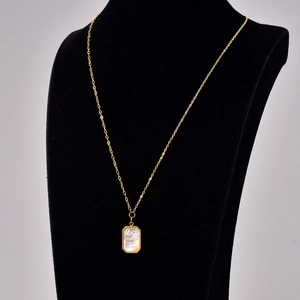 Detail of gold necklace featuring a rectangular shell pendant with Timeless engraving