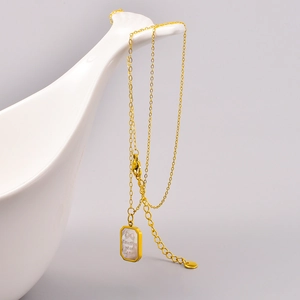 Detail of gold necklace featuring a rectangular shell pendant with a bow design
