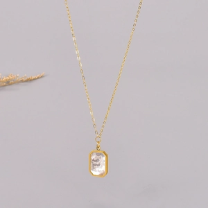 Detail of octagonal gold pendant with white shell inlay and bow tie motif