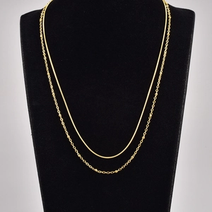 Detail of layered gold double snake chain necklace featuring bead accents on a black bust display
