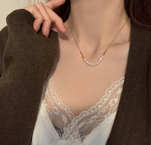 Detailansicht einer natürlichen Süßwasserperlenkette mit Goldkette am Hals des Models