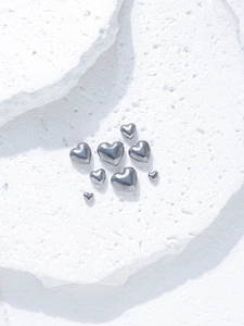 Macro shot of polished silver heart-shaped stainless steel beads for DIY jewelry making