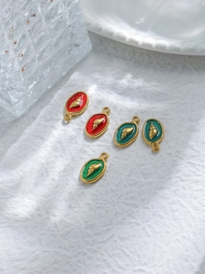 Detail of 18K gold plated shell charms with red and green enamel on white background