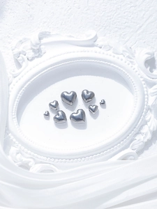 Macro shot of polished stainless steel heart beads on silk for DIY jewelry making