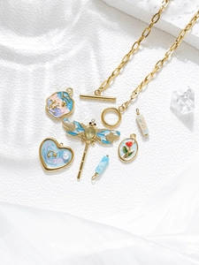 Gros plan d'un collier doré avec pendentifs en émail coloré sur de la soie blanche