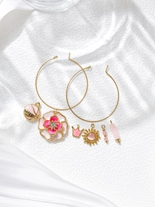 Détail de boucles d'oreilles plaquées or 18K avec breloques émaillées fleurs et couronnes