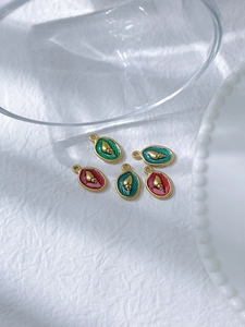 Detailed close-up of 18K gold-plated oval enamel charms with ocean snail relief patterns