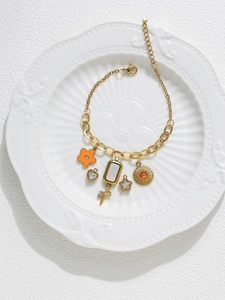 Detailed view of a gold chain bracelet with heart, star, and flower charms on a ceramic plate