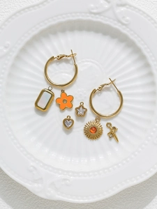 Macro shot of gold DIY jewelry set with charms and earrings on white ceramic plate