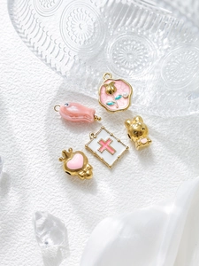 Detailed close-up of pink and gold DIY jewelry charms including rabbit and flower pendants