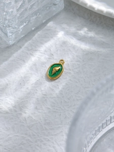 Macro detail of 18K gold shell pendant with emerald green enamel on ripple texture