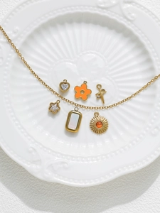 Detail of a gold necklace with six assorted star and heart charms on a ceramic plate