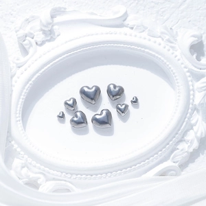 Polished stainless steel heart beads for DIY jewelry making displayed on white silk