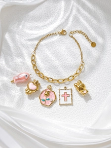 Detail of gold stainless steel charm necklace with pink enamel pendants on white silk