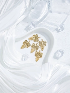Close-up of five golden grape charms on a white heart-shaped plate for jewelry DIY