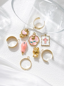 Detailed view of pink enamel crown and heart pendants with gold DIY jewelry accessories