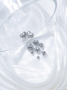 Macro shot of silver heart beads with caviar edge detail for DIY jewelry making