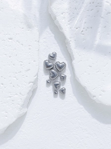 Macro detail of heart-shaped stainless steel beads with delicate beaded edge texture