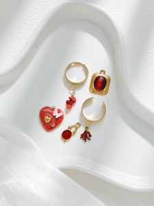 Detalle de colgantes de corazón rojo y anillos dorados para joyería DIY en bandeja