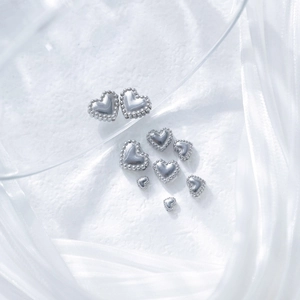Silver stainless steel heart beads in various sizes for DIY jewelry on silk background