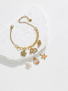 Vue détaillée du bracelet à breloques en acier doré avec pendentifs étoile de mer et éléphant