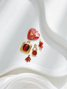 Vista macro de dijes de corazón rojo y colgantes de reloj dorado en plato blanco