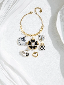 Detail of gold chain bracelet with diverse floral, bag, and hat charms on white stone
