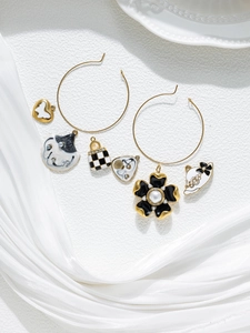 Detail of gold hoop earring set with enamel heart, flower, and fashion bag charms