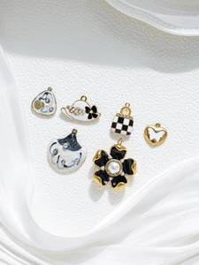 Close-up of enamel charms including checkerboard bag and floral hat for DIY jewelry making