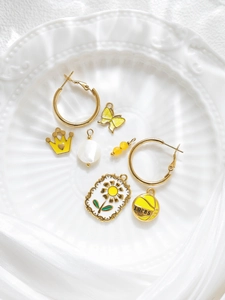Detail shot of golden charms including a yellow crown, butterfly, and enamel flower on a plate