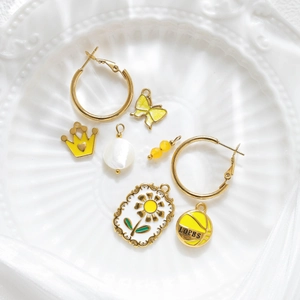 Golden hoop earrings and assorted yellow pendants set in a decorative ceramic tray
