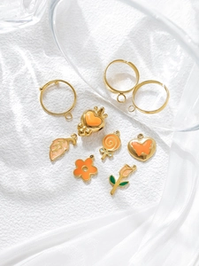 Detail of DIY jewelry kit with golden ring bases and orange enamel flower pendants
