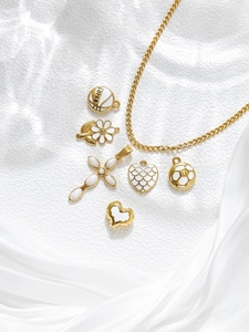 Flat lay of gold stainless steel necklace with heart, cross and daisy pendants set