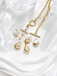 Close-up of golden cross and daisy pendants with white enamel on a thick link chain