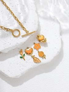 Macro shot of gold OT buckle chain with orange enamel flower and heart charms