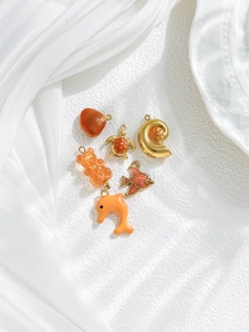 Detailed close-up of marine-themed charms including shell and dolphin on white background