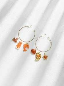 Detailed view of golden hoop earrings with orange fish, dolphin and shell charms