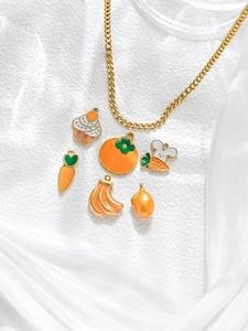 Collar de cadena dorada con dijes de esmalte de zanahoria y cupcake sobre satén