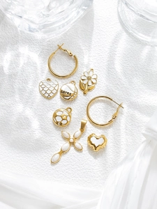 Detailed close-up of gold stainless steel heart and cross pendants on textured fabric