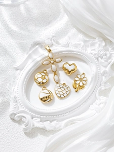 Detailed view of six gold-plated enamel charms featuring a cross, heart, and sunflower