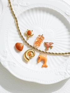 Macro detail of ocean-themed resin charms and gold chain on a ceramic plate
