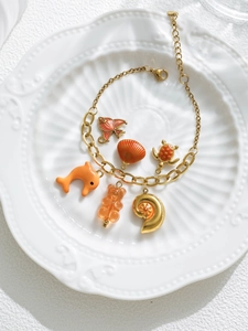 Close-up of ocean-themed bracelet with gold shell, fish, and turtle charms on a white plate