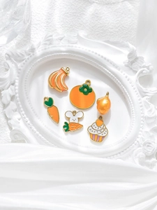Primer plano de dijes de zanahoria y cupcake con esmalte naranja y acabado dorado