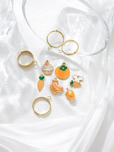Detalle de dijes de esmalte y bases de anillos dorados para la creación de joyas artesanales