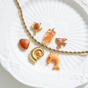 Golden sea theme necklace with orange shells and marine animal charms on a ceramic plate