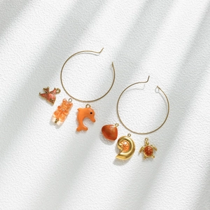 Golden hoop earrings set with ocean-themed pendants including fish shell and gummy bear