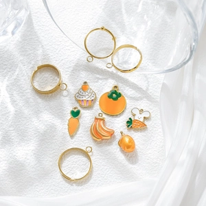 Set de joyería DIY con anillos dorados y colgantes esmaltados de zanahoria y pastel